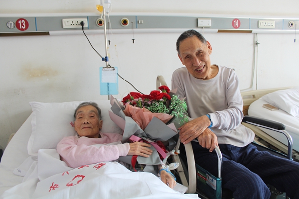 92岁老人坐轮椅在病房为89岁妻子送鲜花庆祝结婚65周年